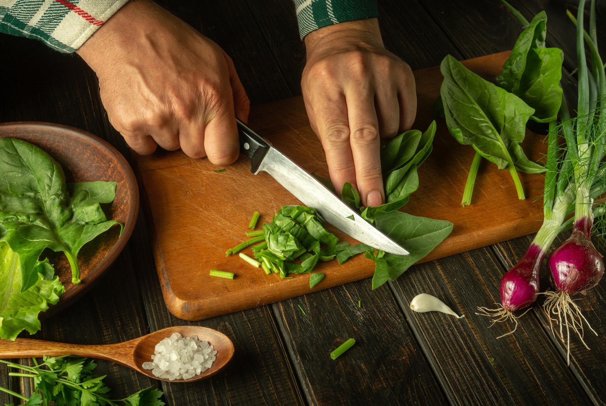 Dettaglio mani chef che affetta erbe fresche